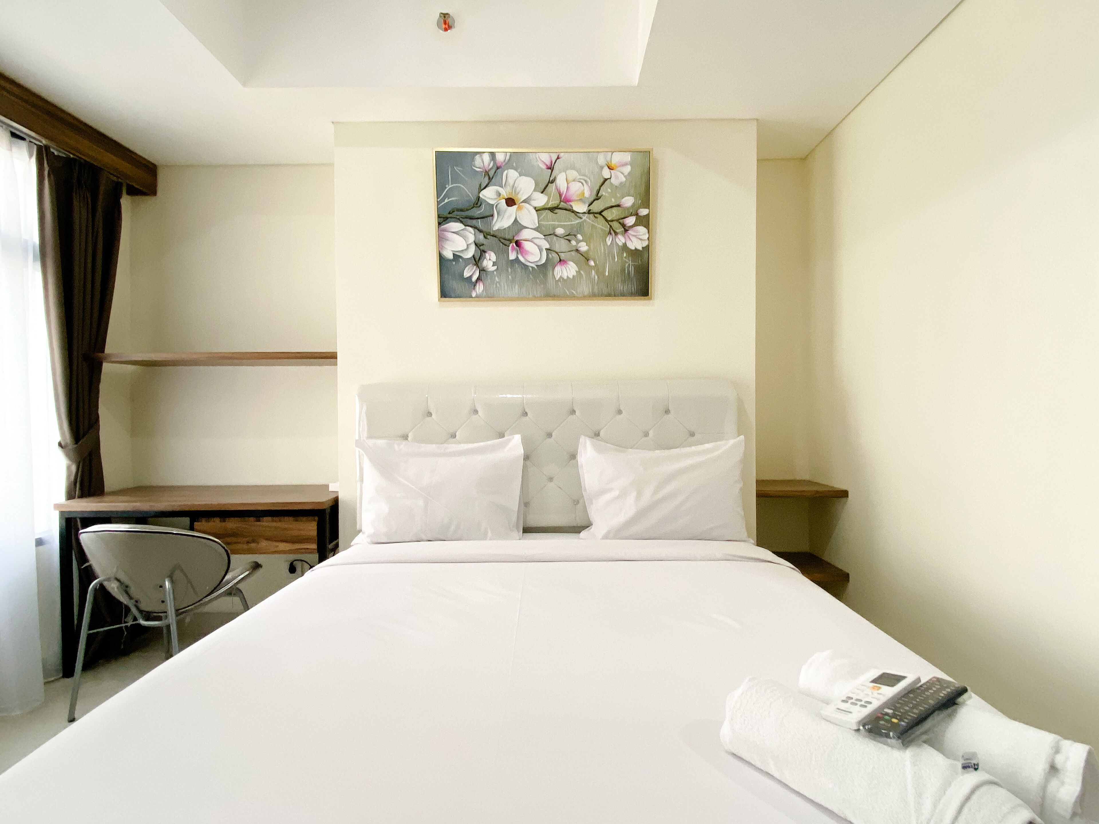 Habitación de hotel con una cama grande, un escritorio, una silla y un cuadro de flores en la pared.