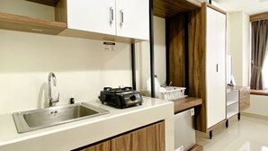 A modern kitchen with a sink, a coffee maker, and wooden cabinets. - Homey And Cozy Stay Studio Room Pollux Chadstone Apartment (Cikarang)