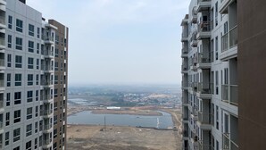 Ein Hochhaus mit mehreren Balkonen und Blick auf eine Baustelle, im Vordergrund ein großes Gewässer.
