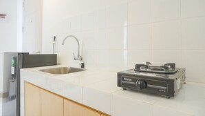 Eine Küche mit Spüle, Kühlschrank und einem tragbaren Gaskochfeld.