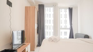 Une chambre d’hôtel avec un lit, une télévision, une armoire et une fenêtre avec des rideaux.