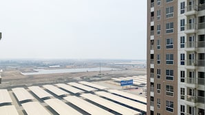 Un immeuble de grande hauteur doté de nombreux balcons et offrant une vue sur un vaste parking abritant de nombreuses structures blanches en forme de parasol.