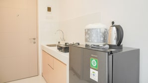 Une cuisine compacte équipée d’un réfrigérateur, d’une bouilloire et d’un petit plan de travail.