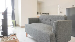 A living room with a grey sofa, a television, and a small table with a power strip.