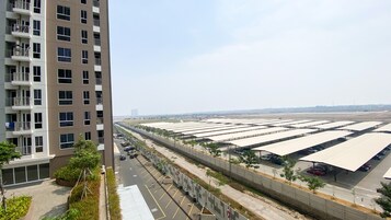 Un edificio de gran altura con varios balcones y un estacionamiento con plazas cubiertas.