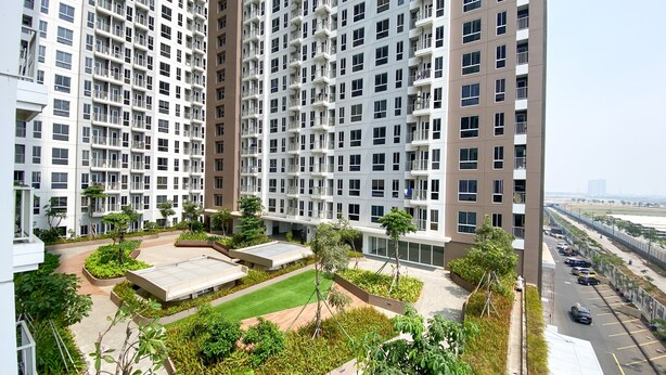 A high-rise residential building with multiple balconies, a rooftop garden, and a parking area.