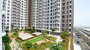 Un edificio residencial de gran altura con múltiples balcones, un jardín en la azotea y un área de estacionamiento.