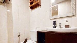 A modern bathroom with a white toilet, a shower, and a vanity with a mirror. - Brand New And Homey Studio At Mataram City Apartment (Ngaglik)