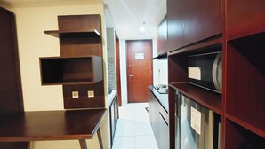 A narrow hallway with a wooden table and cabinets, leading to a door. - Brand New And Homey Studio At Mataram City Apartment (Ngaglik)