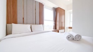 A hotel room with a large bed, a wooden wardrobe, and a window with curtains. - Nice And Homey 2Br At Citra Living Apartment (Jakarta)