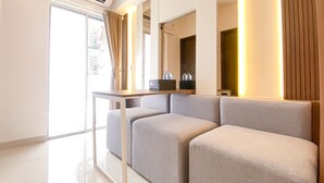 A modern hotel room with a sofa set, a small table, and a minibar. - Nice And Homey 2Br At Citra Living Apartment (Jakarta)