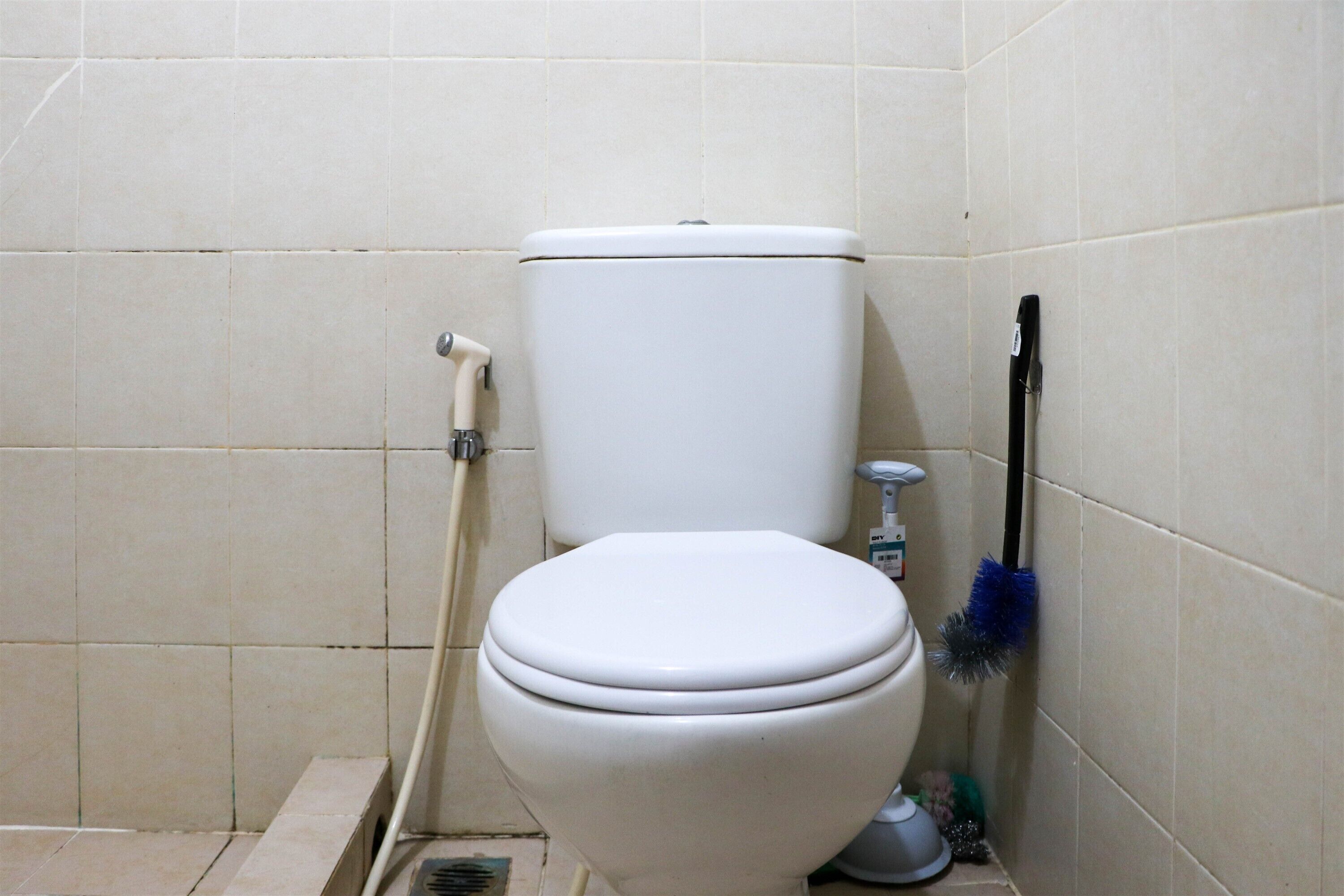 A white toilet in a bathroom with tiled walls and floor.