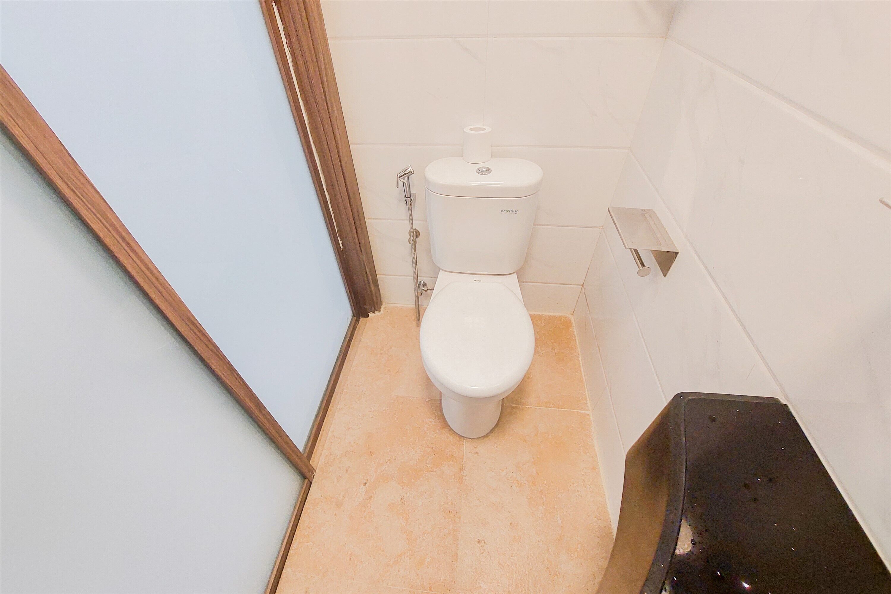 A bathroom with a toilet, a shower area, and a tiled floor.