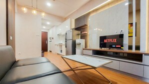 A modern kitchen with a built-in refrigerator, a coffee machine, and a flat-screen TV displaying 'NETFLIX'. - Spacious And Nice 2Br At Sky House Bsd Apartment (Pagedangan)