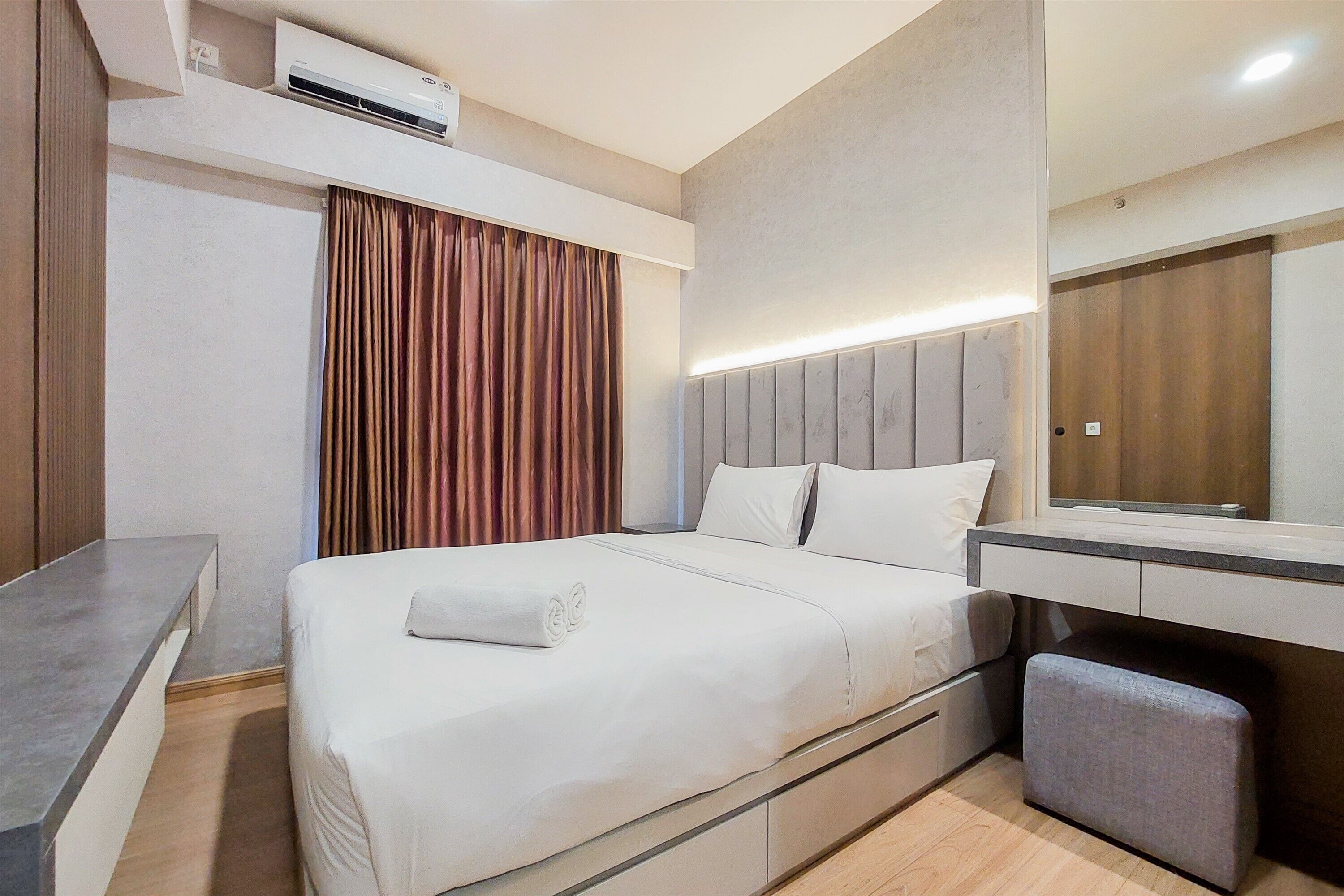 Quarto de hotel moderno com uma cama, uma escrivaninha, um espelho e um aparelho de ar condicionado.