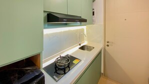 A compact kitchen with a gas stove, a sink, and a cabinet above the counter.