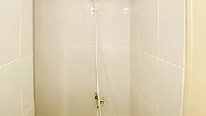 A shower with a handheld showerhead and a wall-mounted faucet.