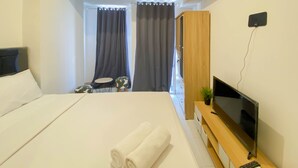 Une chambre d’hôtel avec un lit, une télévision, une armoire en bois et une petite table sur laquelle est posée une plante.