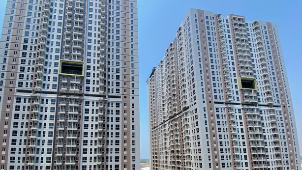 Deux immeubles résidentiels de grande hauteur, dotés de nombreux balcons, se dressent sous un ciel dégagé.