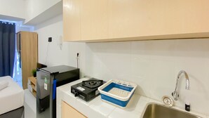 Une cuisine compacte équipée d’un évier, d’un petit réfrigérateur, d’une machine à café et d’un égouttoir bleu.