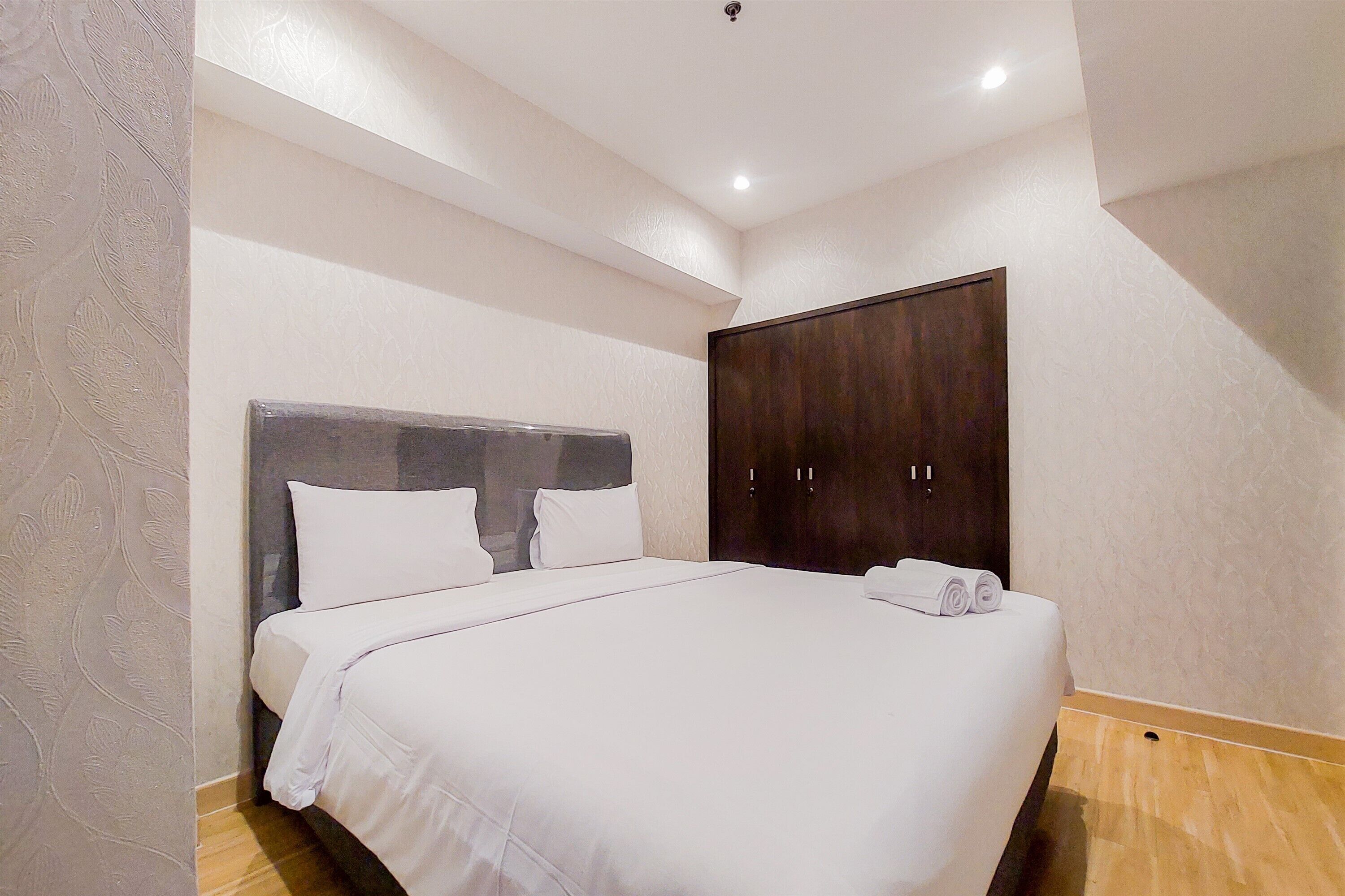 Un dormitorio con una cama grande, un armario y una lámpara en el techo.