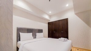 A bedroom with a large bed, a wardrobe, and a ceiling light. - Homey And Tranquil 1Br Branz Bsd City Apartment (Pagedangan)