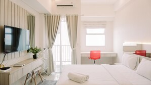 A modern hotel room with a large bed, a flat-screen TV, a desk with a chair, and a window with curtains.