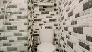 A bathroom with a toilet, a shower, and a sink.