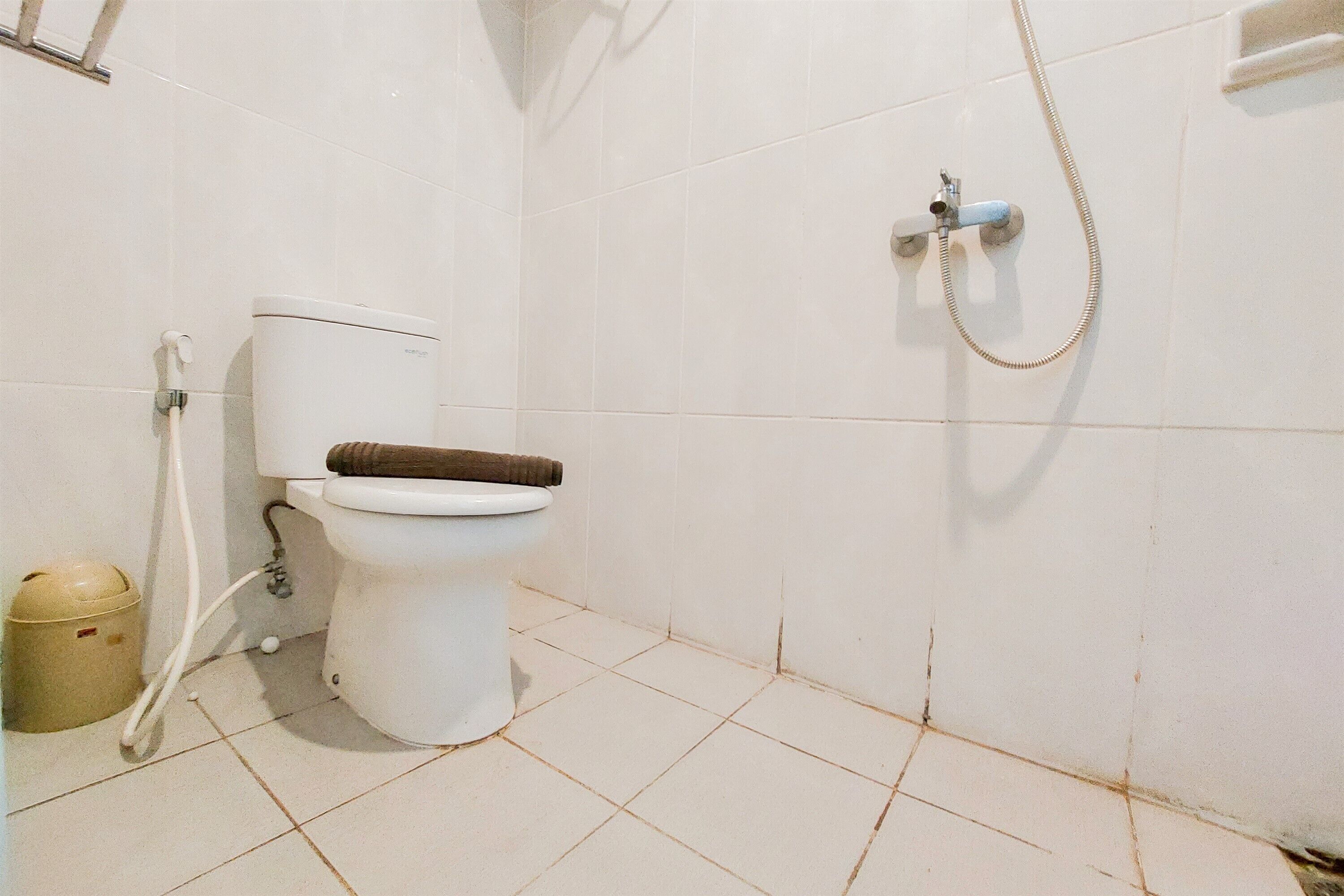 A small, clean bathroom with a toilet, a shower, and a waste bin.