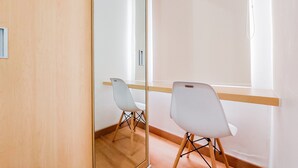A room with a wooden floor, a large mirror, and two white chairs. - Warm And Cozy Living Studio Serpong Garden Apartment (Cisauk)