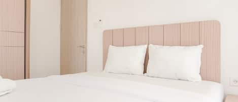 A neatly made bed with a wooden headboard, a white pillow, and a white blanket.