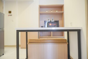 Una kitchenette con un mueble de madera, una encimera negra y un estante con botellas de agua y un letrero de Travelio.