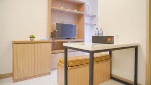 Une petite cuisine équipée avec un téléviseur intégré, des placards en bois, un banc et une petite table.