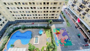 A high-rise building with multiple balconies and a rooftop garden. - Homey And Modern 1Br At Kebagusan City Apartment (Jakarta)