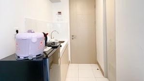A compact kitchen with a refrigerator, a sink, and a white cabinet. - Good Choice And Nice Studio At Tokyo Riverside Pik 2 Apartment (Teluknaga)