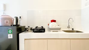 A kitchen with a refrigerator, stove, sink, and various kitchen items. - Good Choice And Nice Studio At Tokyo Riverside Pik 2 Apartment (Teluknaga)