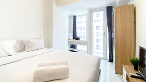 A modern hotel room with a large bed, a wooden wardrobe, a TV, and a window with curtains. - Good Choice And Nice Studio At Tokyo Riverside Pik 2 Apartment (Teluknaga)