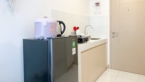 A compact kitchen with a refrigerator, a kettle, a coffee maker, and a sink. - Good Choice And Nice Studio At Tokyo Riverside Pik 2 Apartment (Teluknaga)