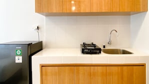Eine Küche mit Holzschränken, einem schwarzen Kühlschrank, einem Gasherd und einer Spüle aus Edelstahl.