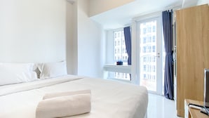 Ein Hotelzimmer mit einem großen Bett, einem Holzschrank, einem Schreibtisch mit Computer und einem Fenster mit Vorhängen.