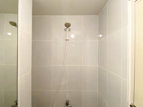 Une douche équipée d’un pommeau de douche à main et d’un robinet mural.