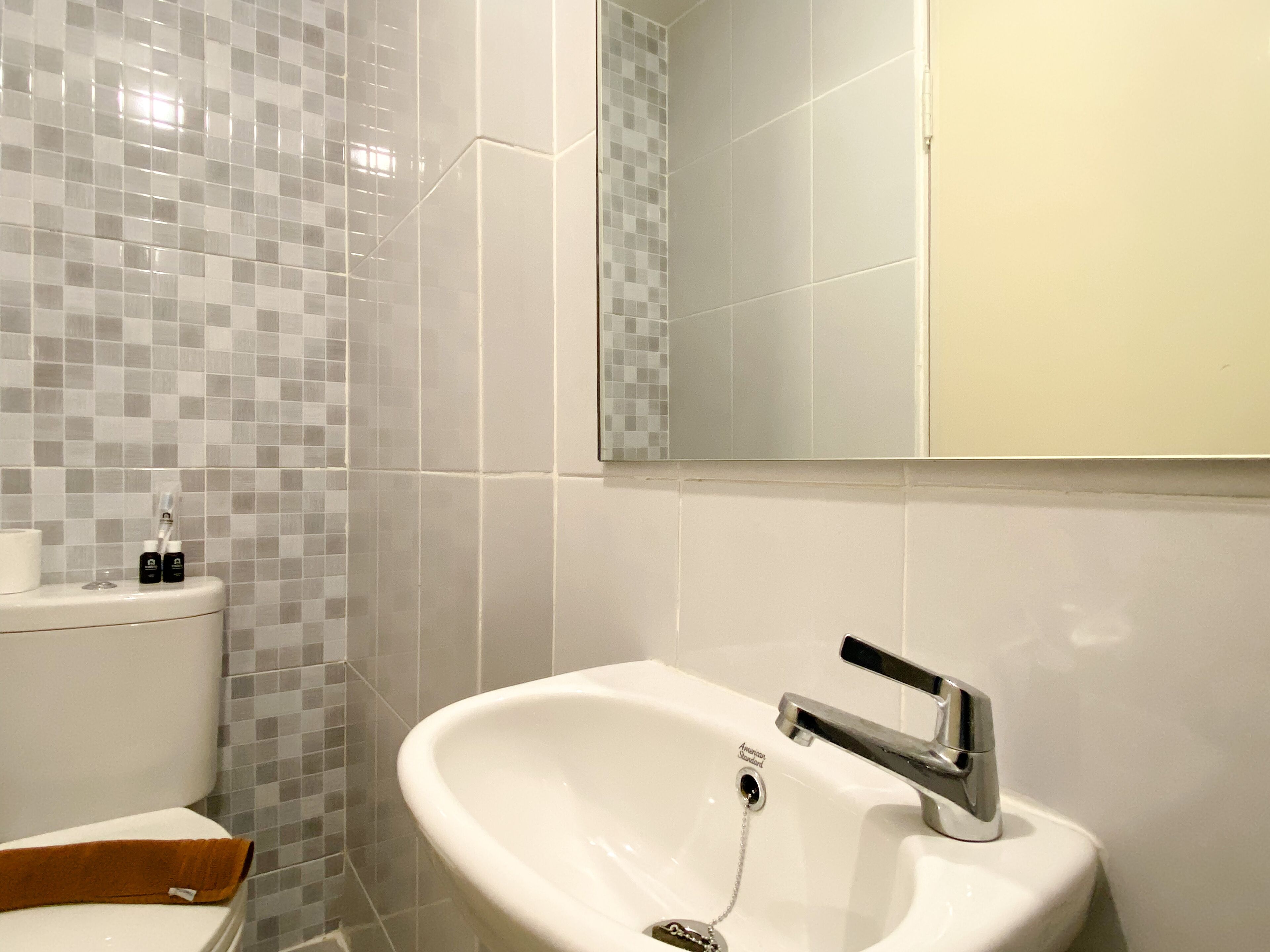 A bathroom with a toilet, sink, and mirror.