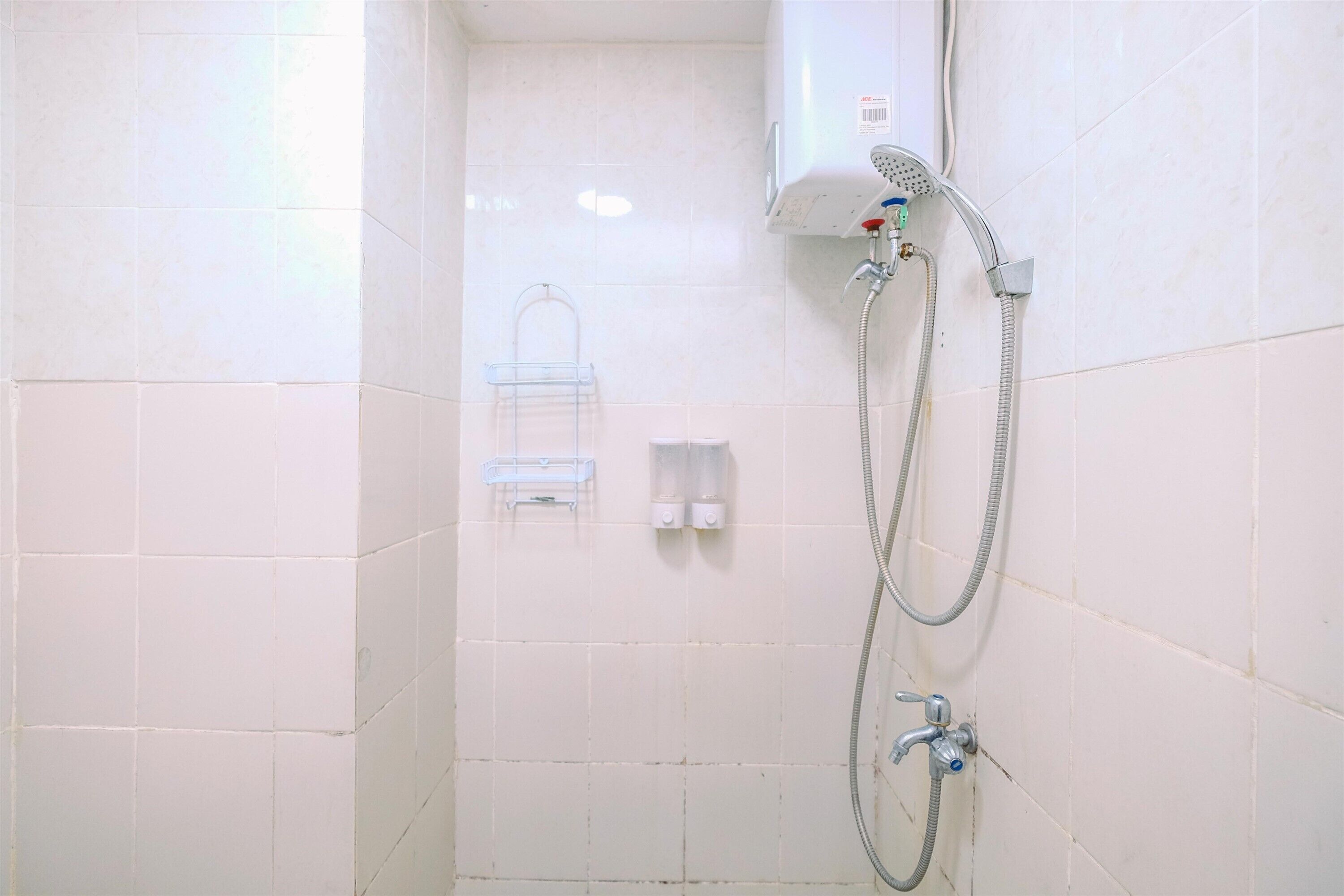 A small, tiled shower area with a handheld showerhead and a wall-mounted faucet.