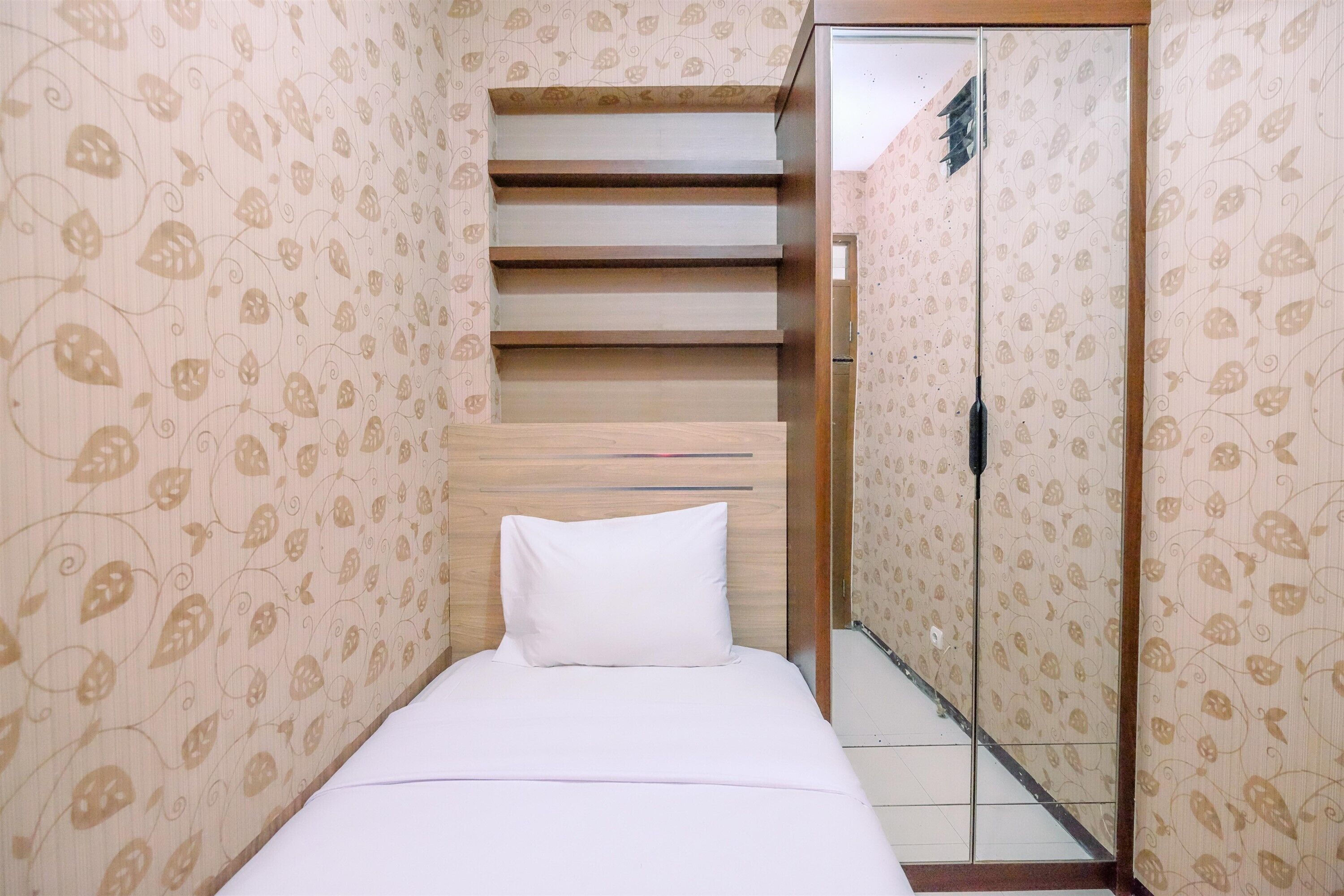 A bedroom with a bed, a wooden headboard, a patterned wallpaper, and a door with a handle.