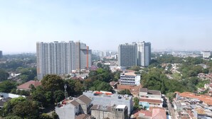 A high-rise building with multiple floors and a flat roof, surrounded by other buildings and greenery. - Strategic And Comfortable 1Br Apartment At Parahyangan Residence (Bandung)