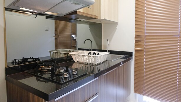 A modern kitchen with a gas stove, a range hood, and wooden cabinets. - Strategic And Comfortable 1Br Apartment At Parahyangan Residence (Bandung)