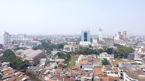 A cityscape with a mix of residential and commercial buildings, including a prominent tower and a lighthouse. - Strategic And Comfy 1Br At Braga City Walk Apartment (Bandung)