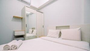 A hotel room with a neatly made bed, a bedside table, a mirror, and a wardrobe. - Well Furnished And Comfy 2Br At Royal Heights Apartment (Bogor)