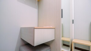 A modern, minimalist room with a built-in bench, a small table, and a chair. - Well Furnished And Comfy 2Br At Royal Heights Apartment (Bogor)