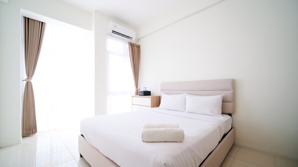 Relax in a serene space with a neatly made bed, bedside table, and large window.